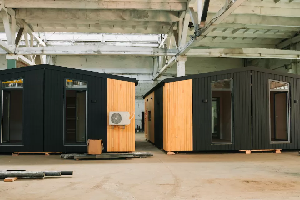 Two black modular units with glass doors and wood accents in an industrial warehouse.